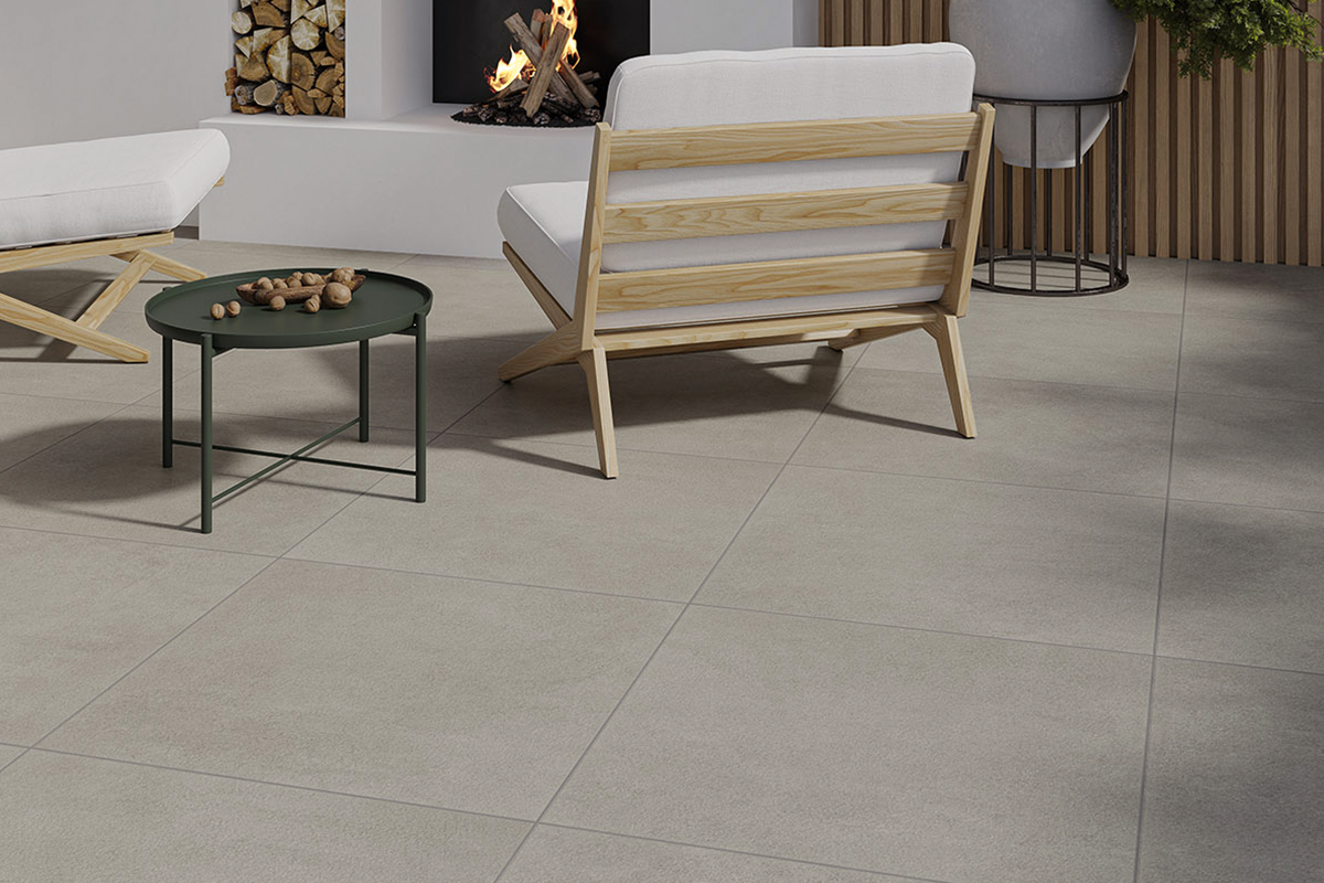 Grootformaat vloertegels van keramiek met betonlook in een lichte, moderne loungeruimte met haard en houten meubels.