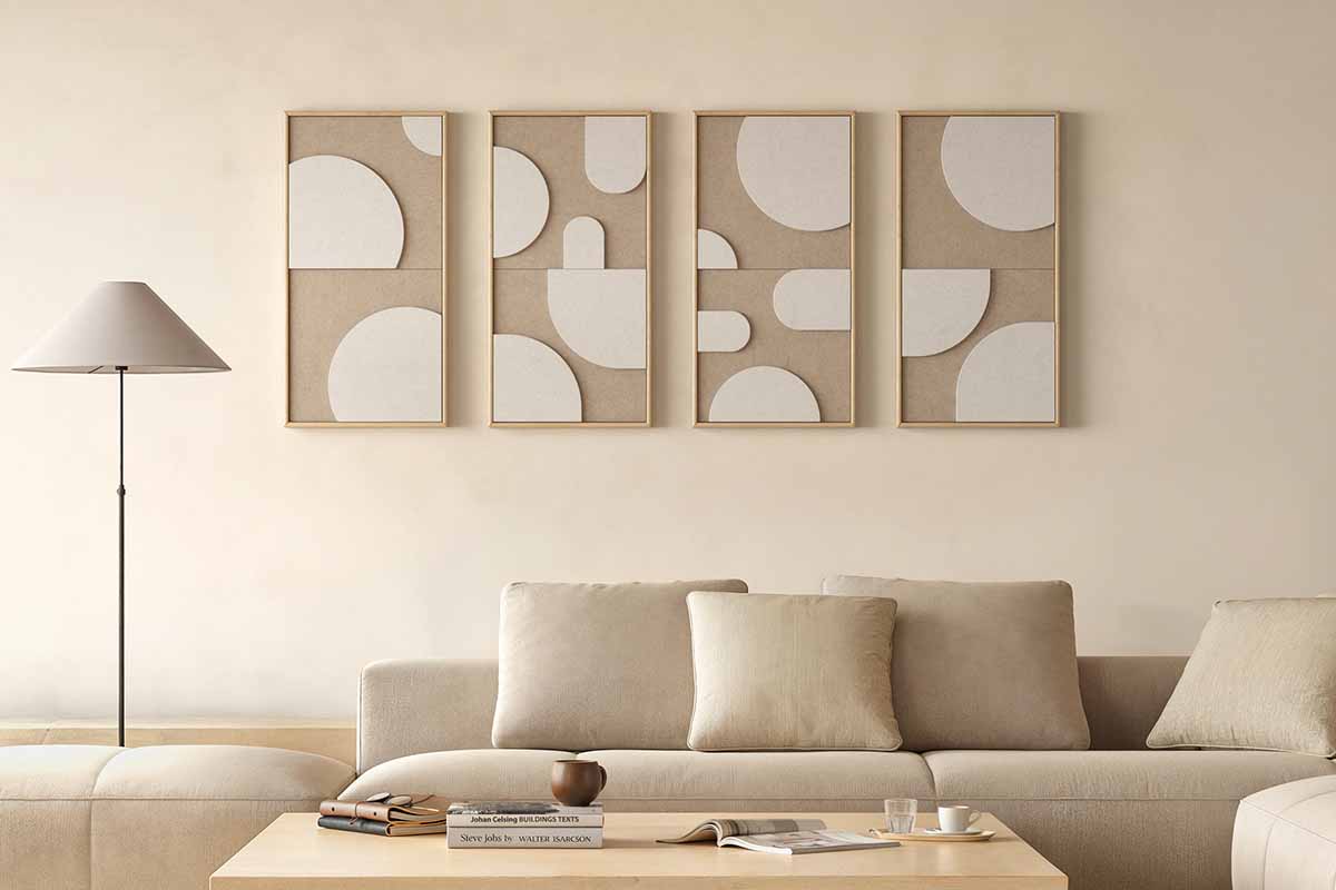 Lichte woonkamer met vier abstracte wanddecoraties in houten lijsten, een bank met kussens, een vloerlamp en een houten salontafel.
