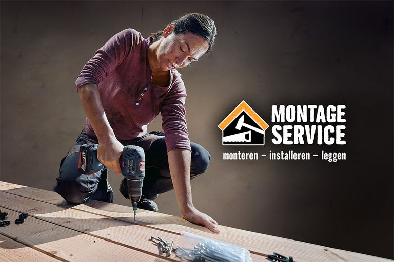 Een vrouw werkt met een accuschroevendraaier aan een houten terras, met op de achtergrond het logo van de montageservice.