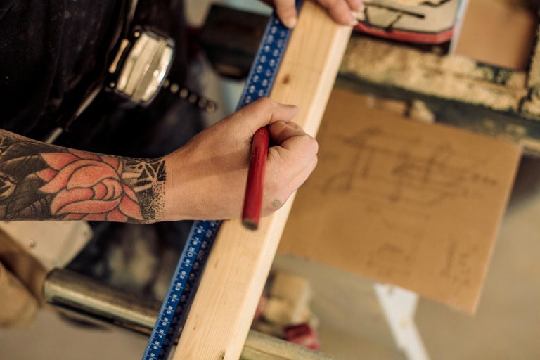 Ambachtsman markeert een stuk hout met een potlood en een blauwe liniaal