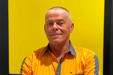 Portret van een man in werkkleding voor een gele achtergrond