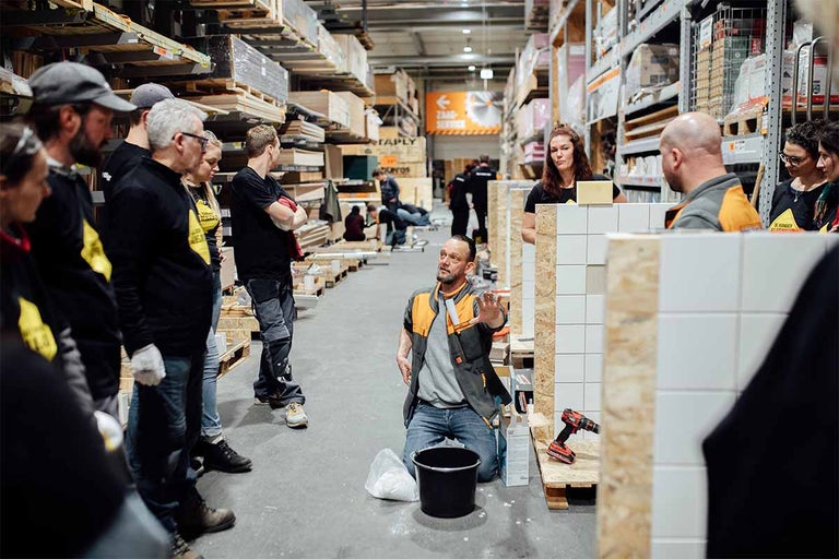 Cursus tegelzetten in de Hornbach-bouwmarkt met deelnemers en instructeur.