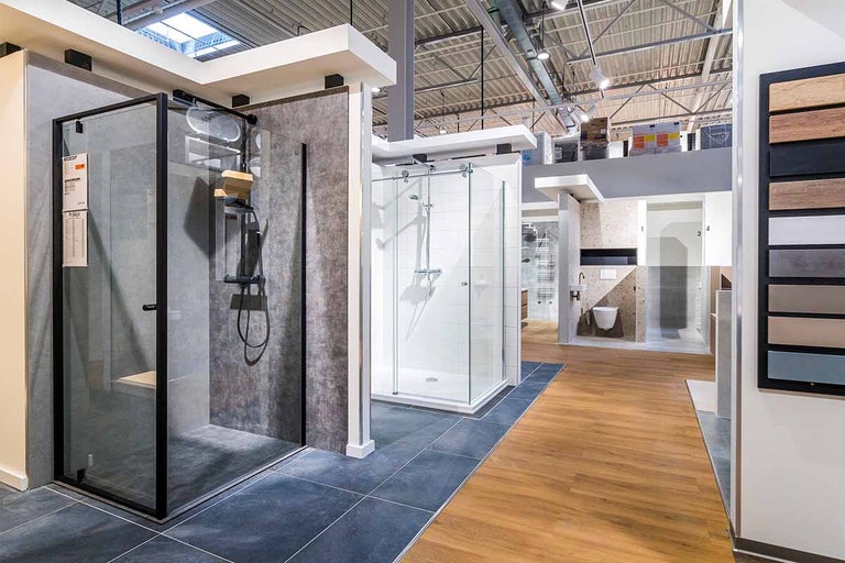Showroom met verschillende douchecabines en badkameropstellingen in een bouwmarkt.