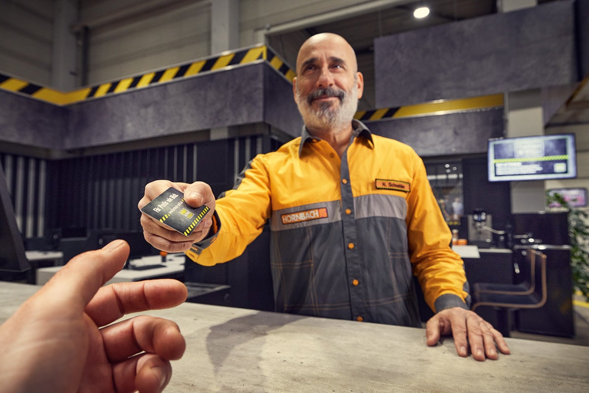 Een Hornbach medewerker overhandigt een klantenkaart aan een klant.