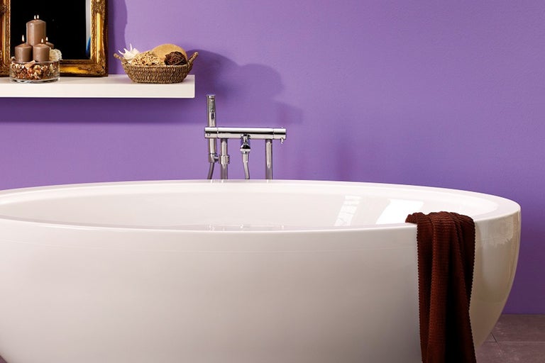 Badkamer met vrijstaand bad, kraan en decoratieve items op een plank