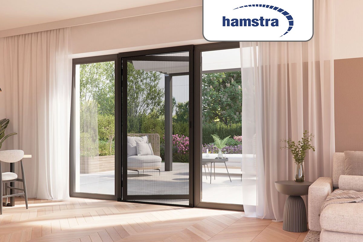 Hamstra plissé hordeur voor een terrasdeur in een lichte woonkamer met houten vloer. Hamstra Logo.