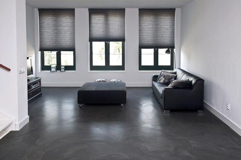 Woonkamer met bank, rolluiken en epoxyvloer