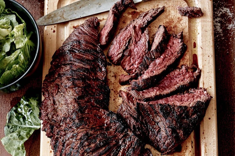 Gegrild en gesneden rundvlees op een houten plank met salade