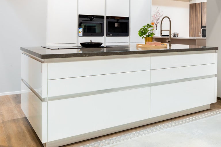 Keukeneiland met laden, kookplaat, spoelbak en inbouwapparatuur in een lichte ruimte