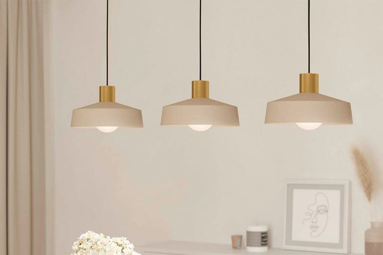 Drie metalen hanglampen met lampenkappen boven een dressoir