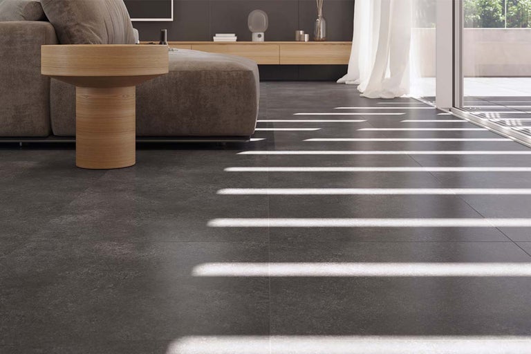 Woonkamer met vloertegels in steenlook, bank en bijzettafel.