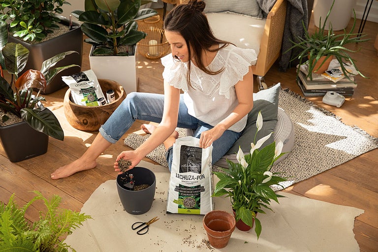 Vrouw verpot kamerplanten met Lechuza Pon in appartement