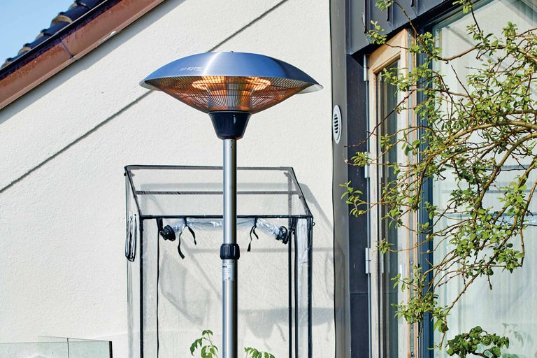 Metalen terrasverwarmer buiten naast een kas