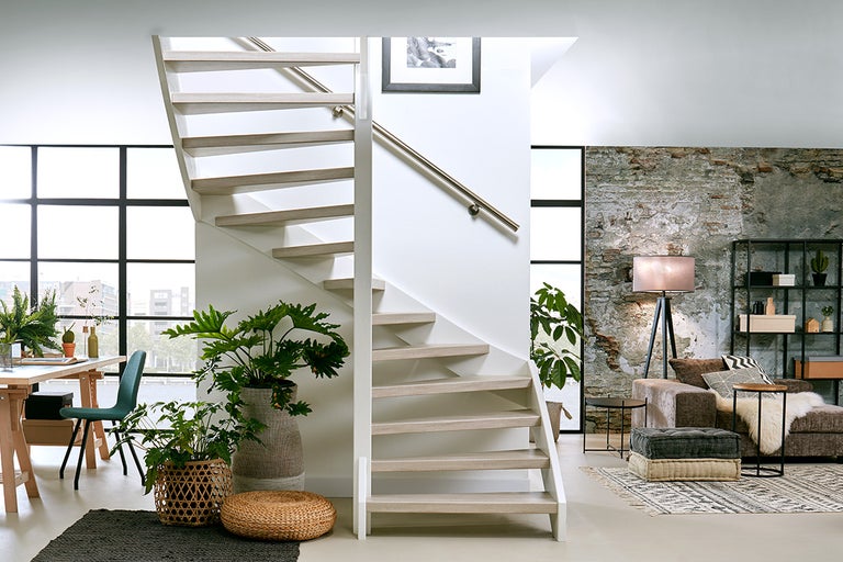 Lichte ruimte met trap, eettafel en zithoek.
