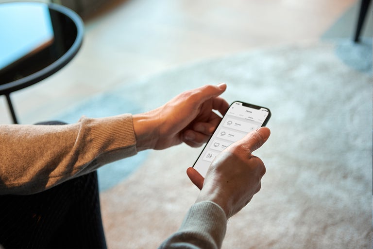 Iemand bedient een smart home app op een smartphone.