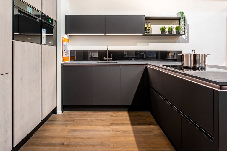 Moderne keuken met zwarte kasten, houtlook en roestvrijstalen pannen