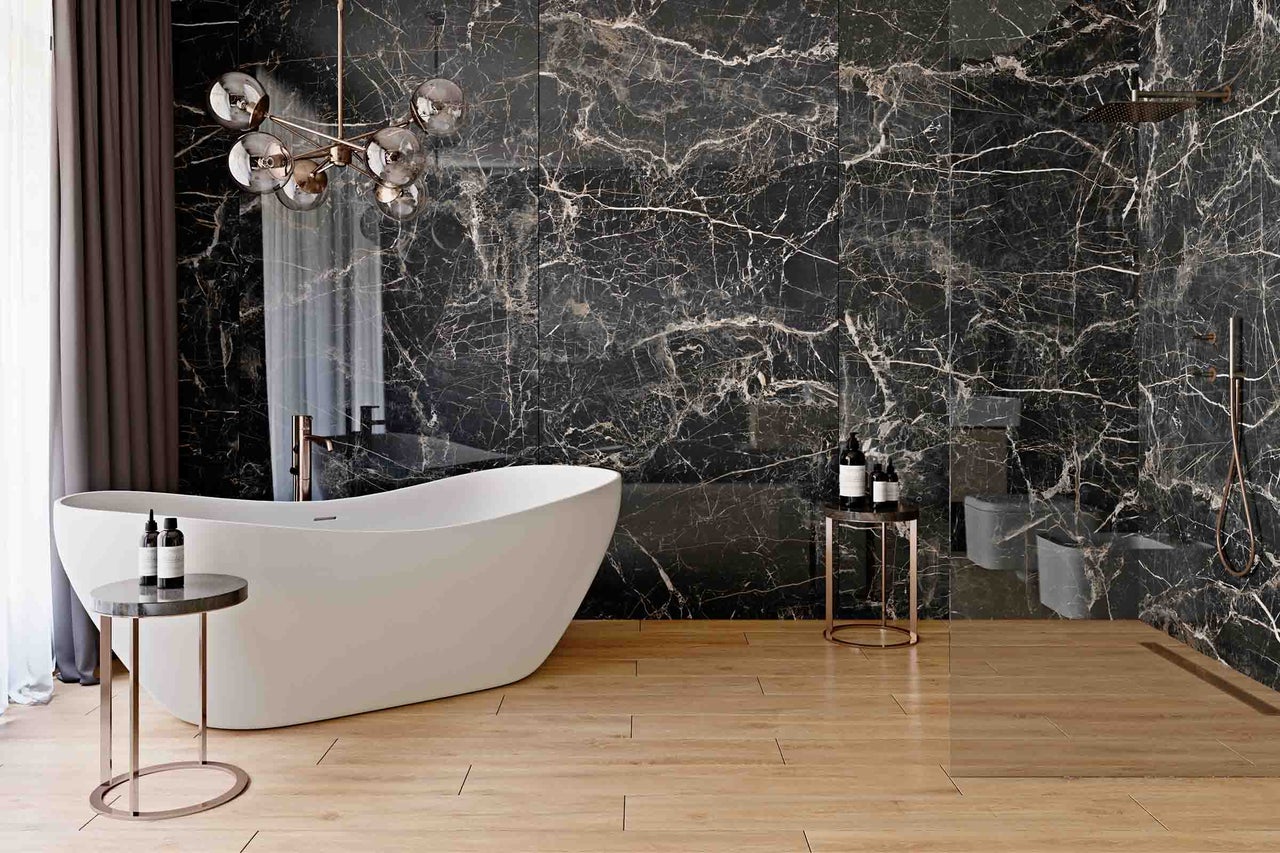 Badkamer met vrijstaand bad, bijzettafels en wandtegels met marmerlook