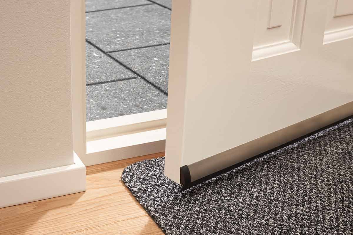 Detailweergave van een deur met deurafdichting en een deurmat in de entree