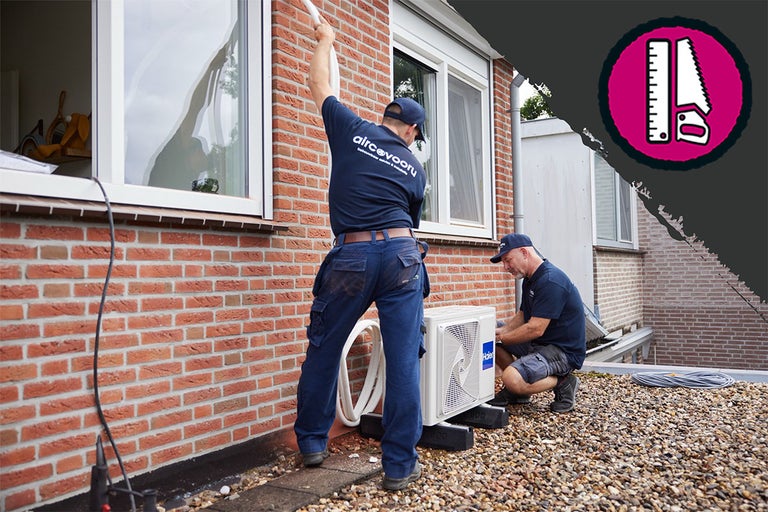 Installatie van een airconditioningsysteem door vakmensen bij een huis met bakstenen muren.