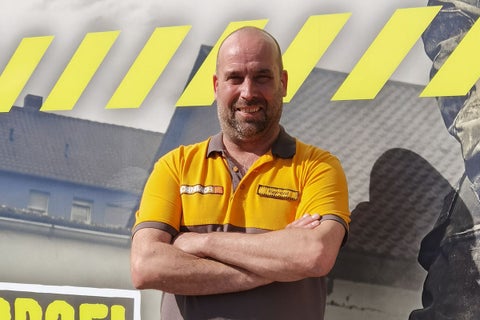 Een Hornbach medewerker met gekruiste armen voor een achtergrond met het Hornbach logo.