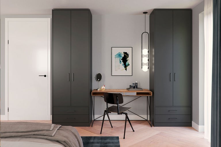 Slaapkamer met grijze kasten, houten tafel, stoel en lamp