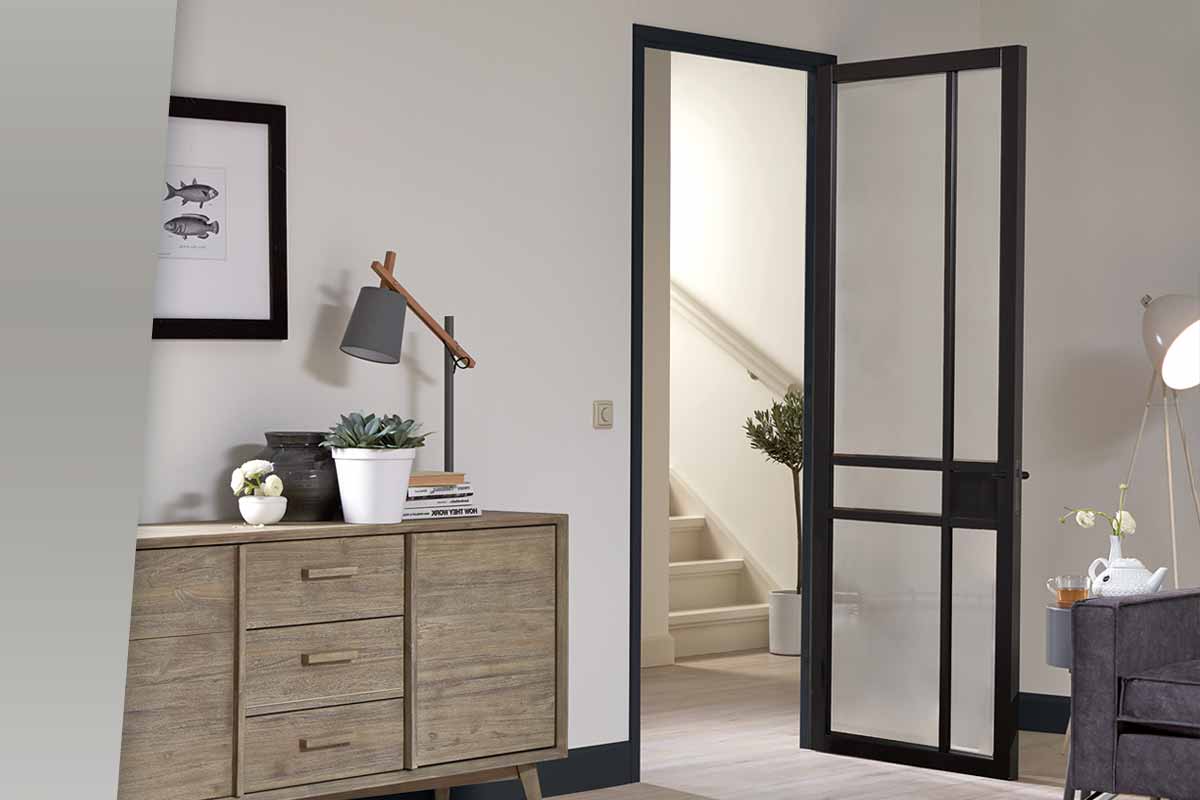 Interieur van een kamer met een moderne stalen frame deur, een houten dressoir en decoratieve elementen.