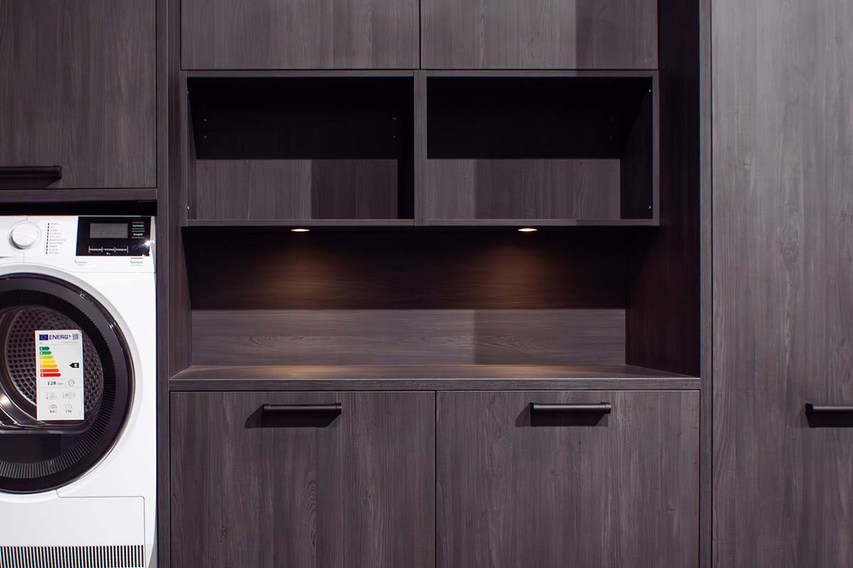 Wasruimte met wasmachine, droger en grijze houten kasten