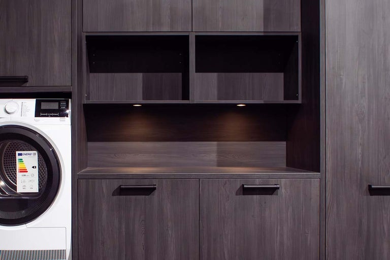 Wasruimte met wasmachine, droger en grijze houten kasten