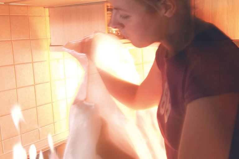 Een persoon blaast in een transparante zak in een keuken.