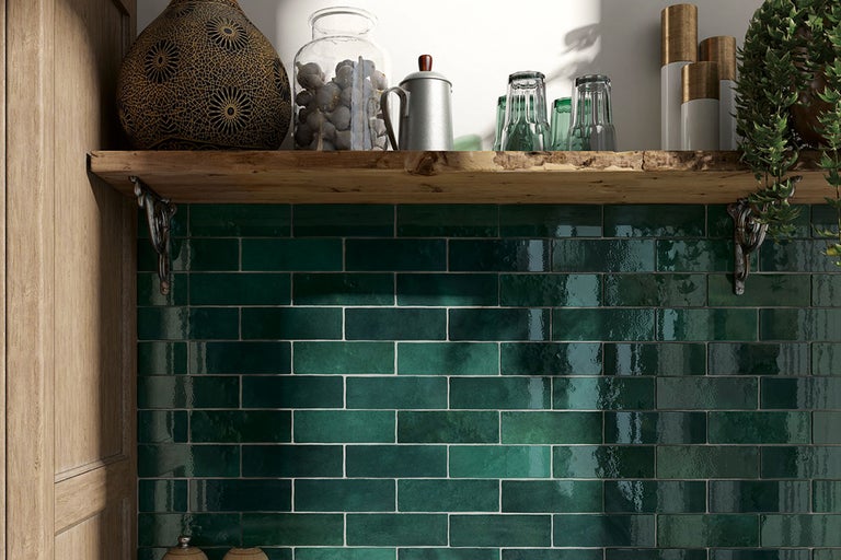 Wanddecoratie met groene tegels in een keuken met een houten plank en decoraties.