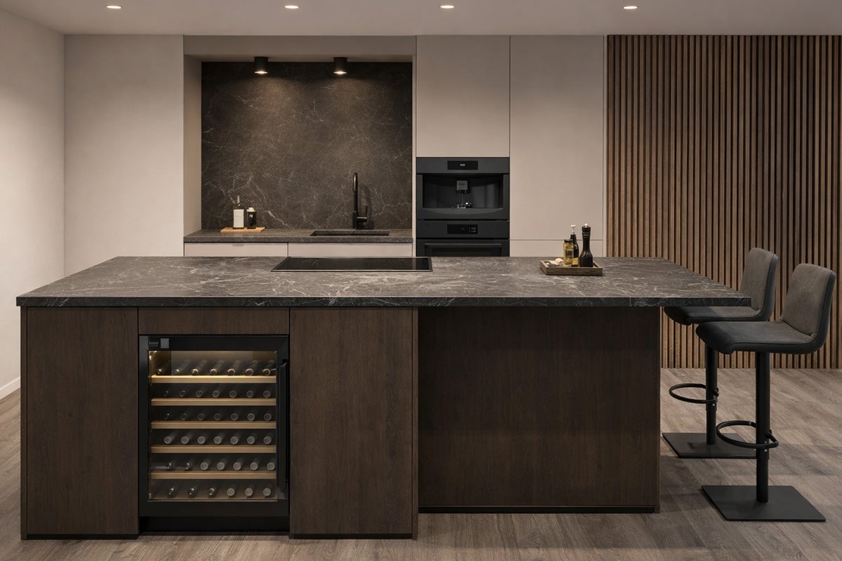 Kookeiland met wijnkoelkast, kookplaat en twee barkrukken in een modern ontworpen keuken