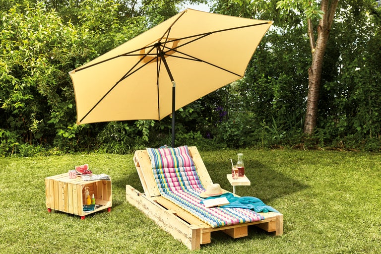 Tuinscene met parasol, ligstoel van houten pallet en bijzettafel