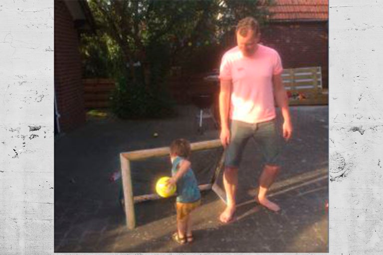 Man en kind spelen met een bal op een erf