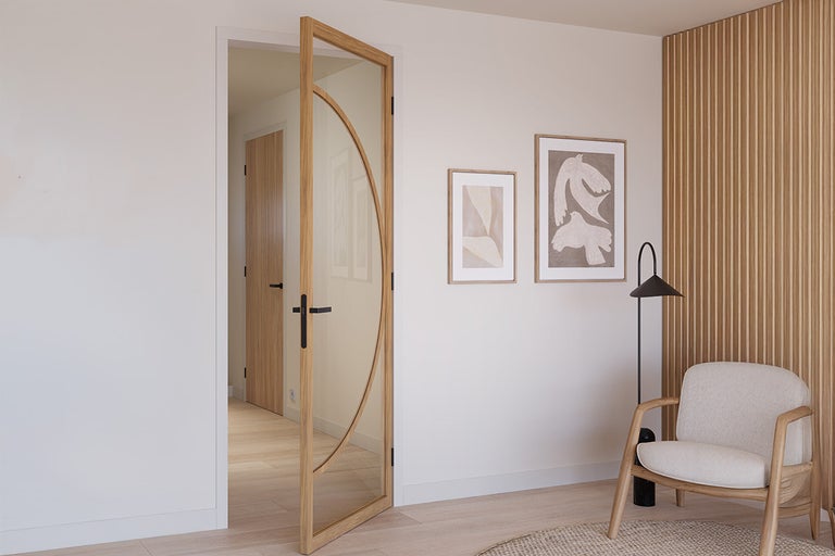 Open glazen deur met houten frame en zwarte deurklink in een lichte kamer.