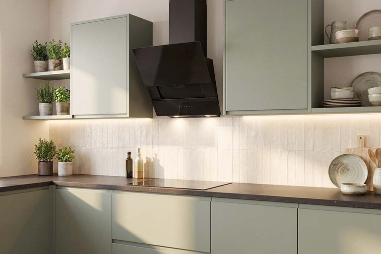 Moderne keuken met groene fronten, donker werkblad, zwarte schuine afzuigkap en ingebouwde ledverlichting.