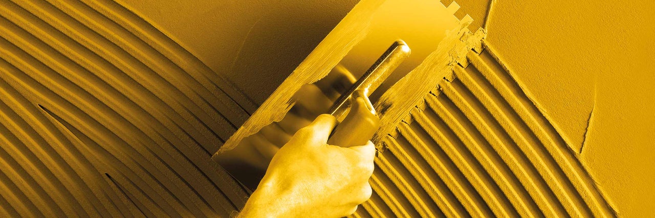 Tegellijm wordt aangebracht met een spaan