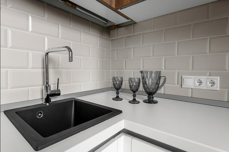 Keukenspoelbak met kraan, glazen en stopcontacten in een moderne keuken.