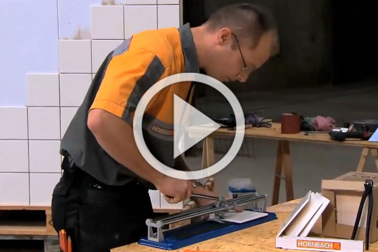 Een man snijdt tegels met een tegelsnijder. Hornbach Logo.