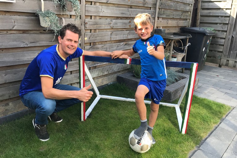 Vader en zoon staan met een voetbaldoel in de tuin