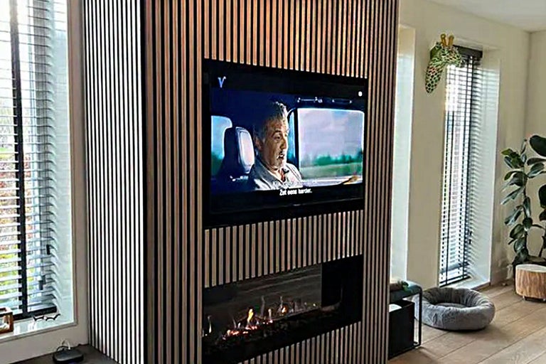 Woonkamer met houten lambrisering, televisie en open haard