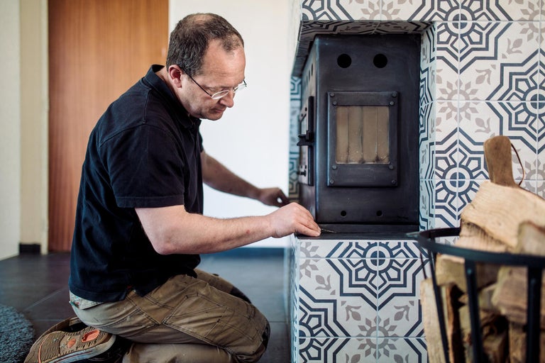 Ambachtsman installeert kachel met versierd tegelwerk