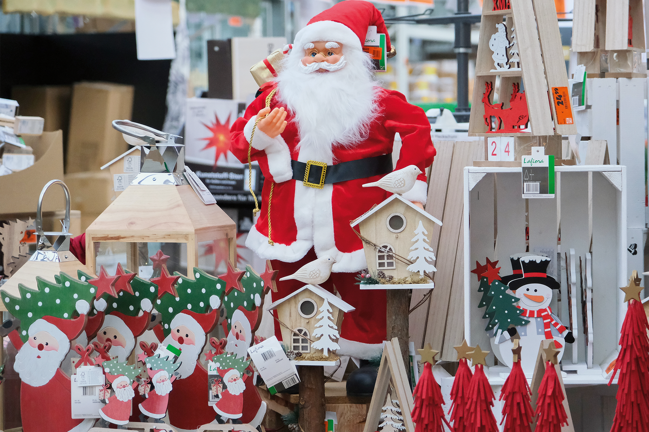 Decoratieve kerstman met kerstversieringen zoals lantaarns, vogelhuisjes en houten figuren.