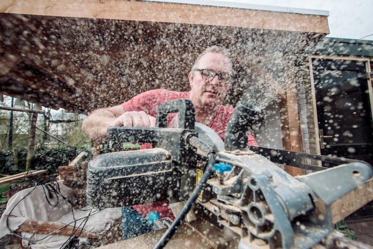 Man zaagt hout met een paneelzaag, zaagsel vliegt