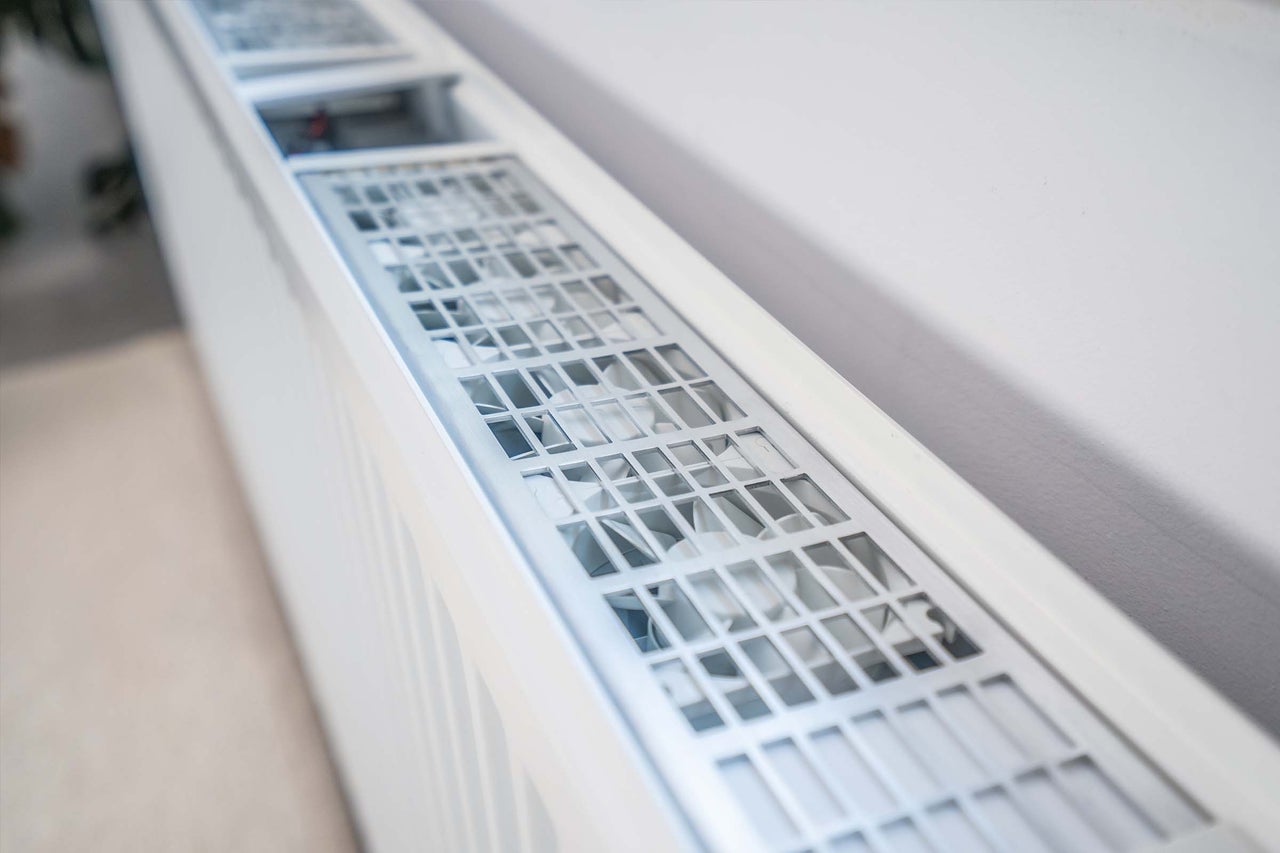 Close-up van een witte radiator met ventilatierooster