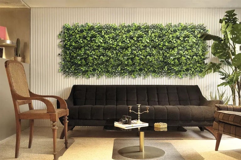 Woonkamer met groene plantenwand boven een bank.