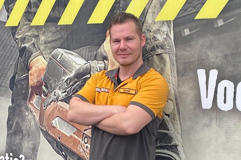 Een man in een Hornbach poloshirt staat voor een fotowand.