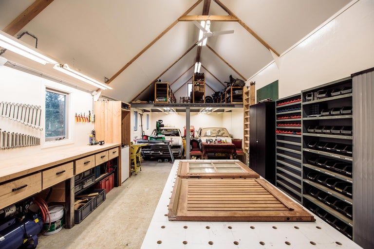 Werkplaats met werkbank, rekken, gereedschap en twee oldtimers