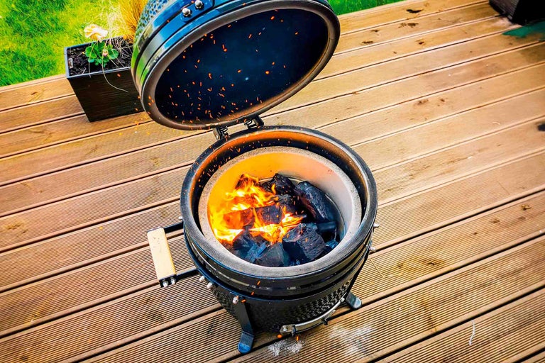 Keramische barbecue met houtskool op een houten terras