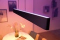 Moderne smarte hanglamp in balkvorm boven een eettafel met sfeervolle verlichting in de woonkamer