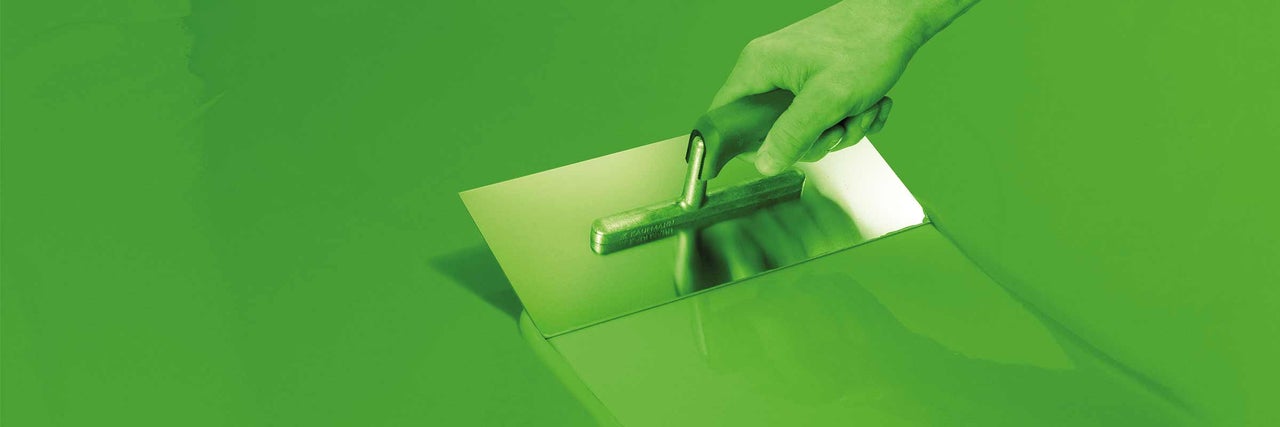 Hand met gladde spaan bij het verwerken van dekvloer